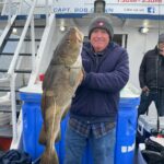 a man and a woman standing in front of a fish