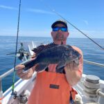 a man holding a fish on a boat in the water