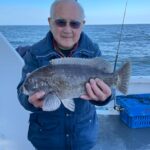 a man holding a fish on a boat in a body of water