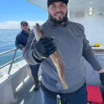 a man holding a fish on a boat posing for the camera