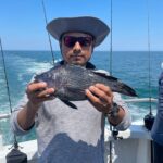 a man holding a fish on a boat in a body of water