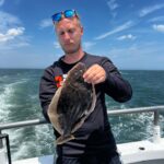 a man holding a fish in front of a body of water